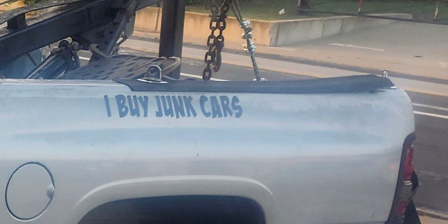 &lsquo;I Buy Junk Cars&rsquo; lettered along the bedside, boom and chains above.