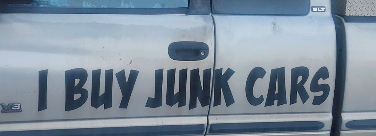 Close-up of &lsquo;I Buy Junk Cars&rsquo; hand-painted along the truck door.