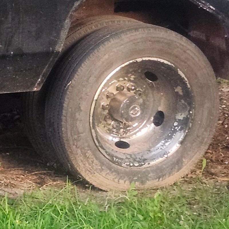 A rear dually wheel on the wrecker, caked in dirt.